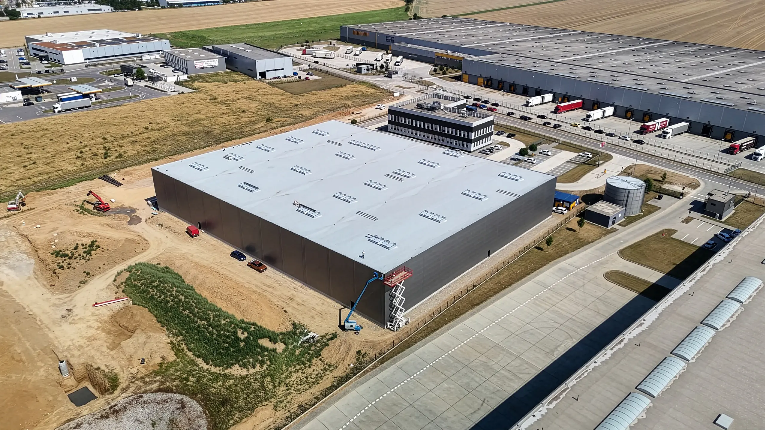 Industrial project Dubnica 4 – construction of a new warehouse and administrative hall in Dubnica nad Váhom. The photo shows a new, completely sheathed hall that will connect to the existing buildings of the industrial park. - obrázok 3
