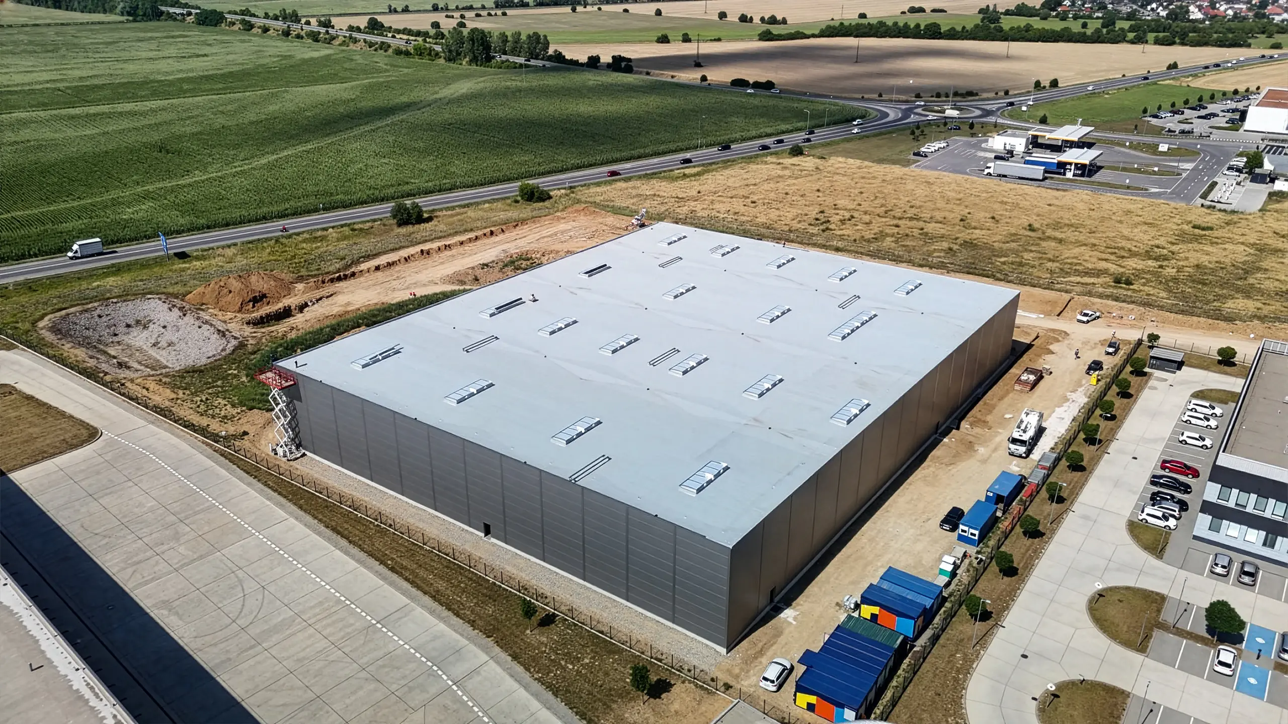 Industrial project Dubnica 4 – construction of a new warehouse and administrative hall in Dubnica nad Váhom. The photo shows a new, completely sheathed hall that will connect to the existing buildings of the industrial park. - obrázok 4