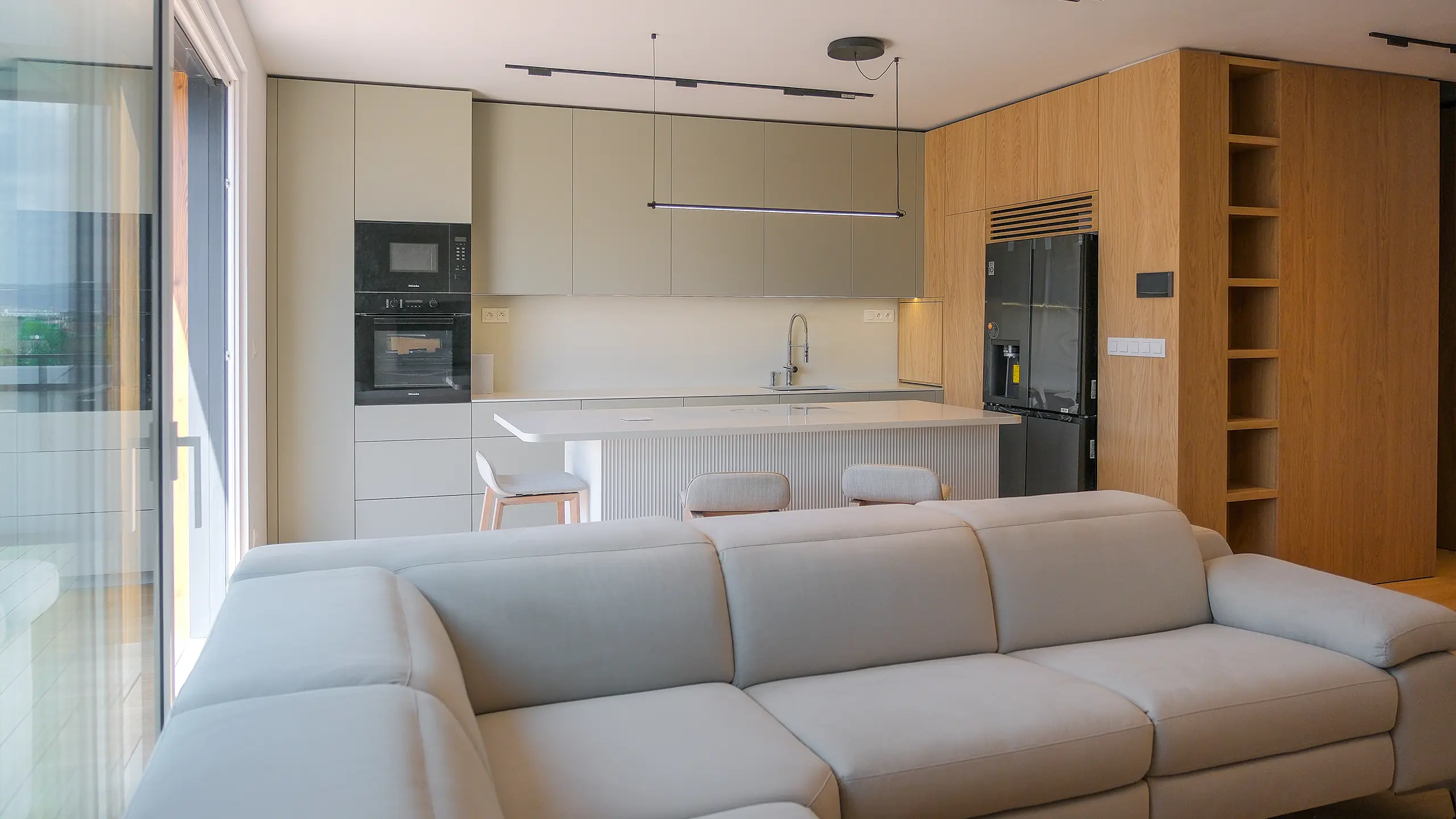 Laurin dvor residential project – modern interior of a show apartment in Bratislava featuring an open-plan living room and kitchen. Premium materials, clean design and large-format glazing create a bright and comfortable living environment for everyday life. - obrázok 12
