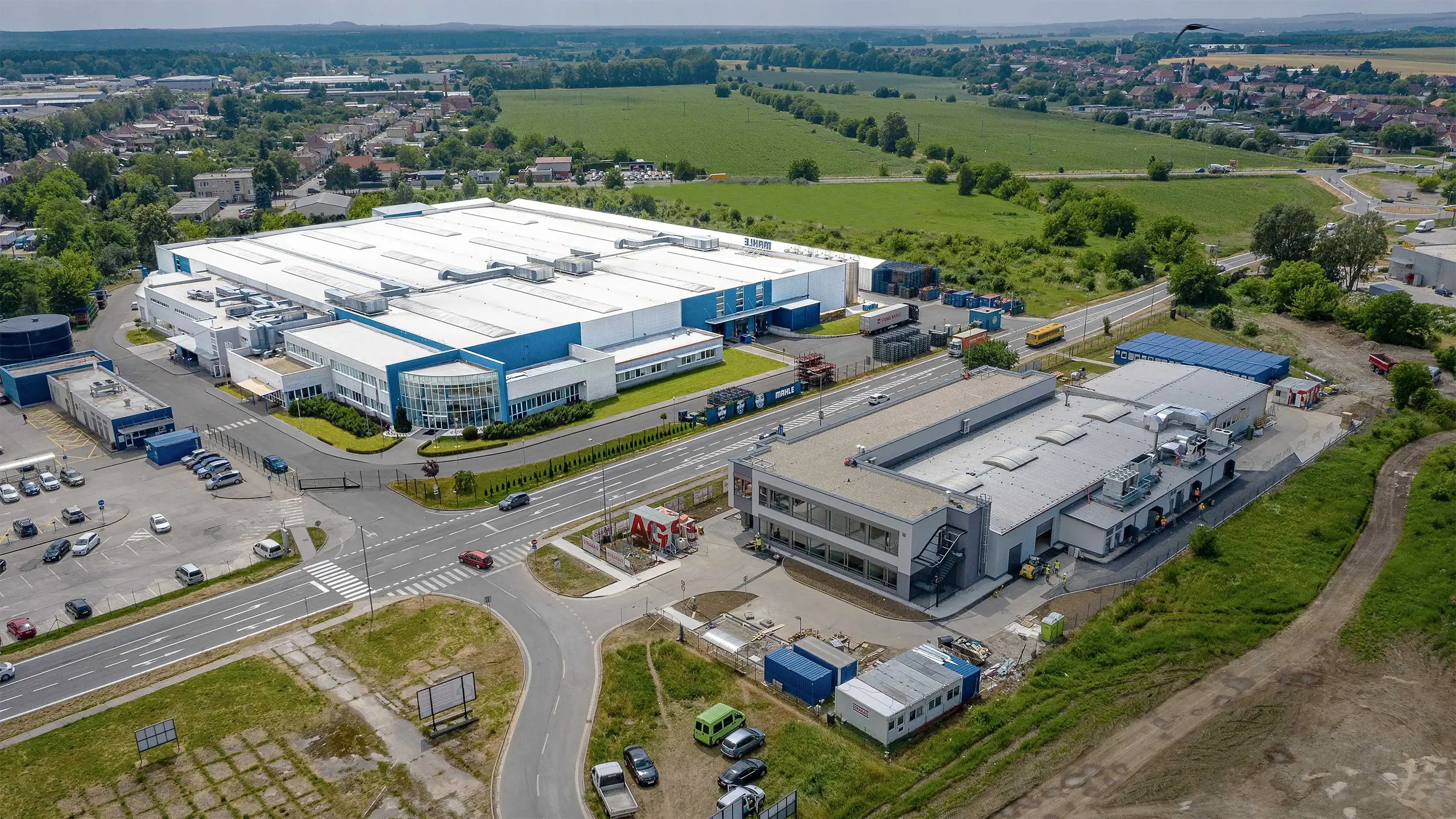 Industrial Project Senica 1 – Aerial view of a manufacturing and warehouse complex leased to an international automotive company, complemented by a newly developed research and development center. The modern industrial facilities are located in a strategic area with excellent access to the D2 motorway and provide extensive production, storage, and office space. - obrázok 1