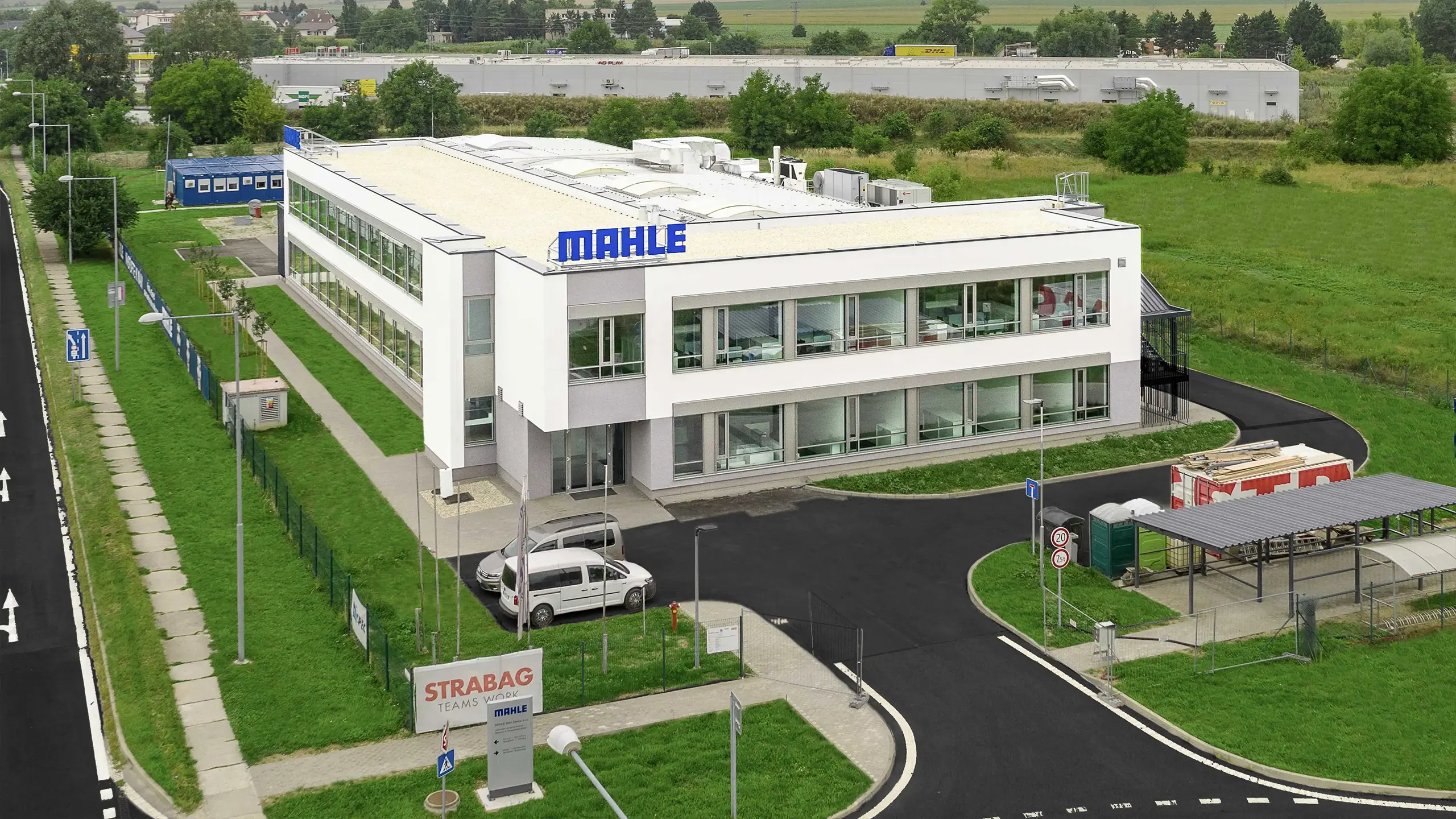 Priemyselný projekt Senica 2 – Letecký pohľad na novovybudované výskumné a vývojové centrum pre medzinárodnú automotive spoločnosť v Senici. Moderná trojpodlažná administratívno-vývojová budova je súčasťou priemyselného areálu s výrobno-skladovacími priestormi a slúži na vývoj automobilových chladiacich systémov. - obrázok 3