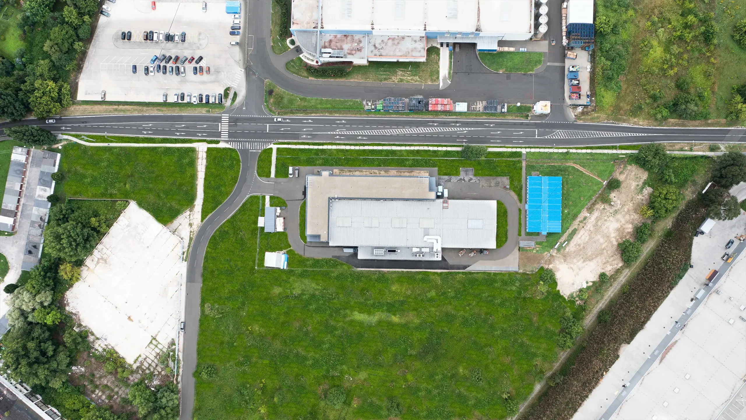 Priemyselný projekt Senica 2 – Kolmý letecký pohľad na výskumné a vývojové centrum a jeho okolie v priemyselnej zóne Senice. Fotografia zachytáva usporiadanie budovy, prístupové komunikácie, technickú infraštruktúru a priestor pre ďalší rozvoj areálu určeného pre medzinárodnú automotive spoločnosť. - obrázok 4