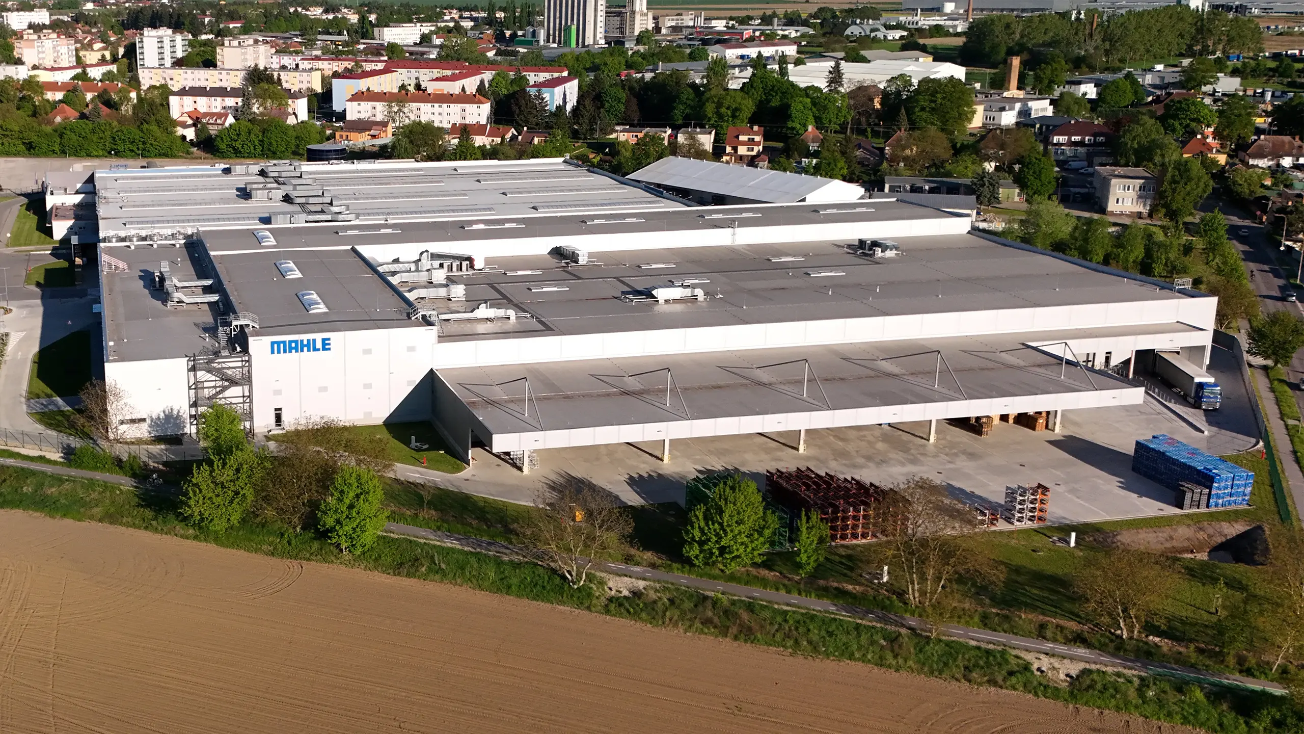 Industrial project Senica 3 – modern manufacturing and warehouse facility for an international automotive company in Senica with expanded production capacity, loading docks and logistics infrastructure. The aerial view captures the extensive MAHLE industrial complex in a strategic location with excellent access to the D2 motorway and strong long-term development potential. - obrázok 2