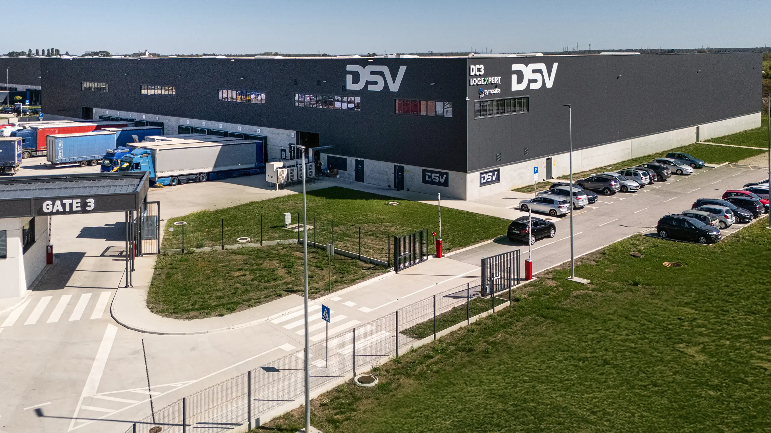 Priemyselný projekt Záhreb 2 – moderná logistická hala s nájomcom DSV v druhej etape logistického parku pri Záhrebe. Fotografia zachytáva skladový objekt s nakladacími rampami, parkovacími plochami pre zamestnancov a kamiónovou obsluhou, navrhnutý pre efektívne logistické a distribučné operácie podľa najvyšších priemyselných štandardov. - obrázok 2