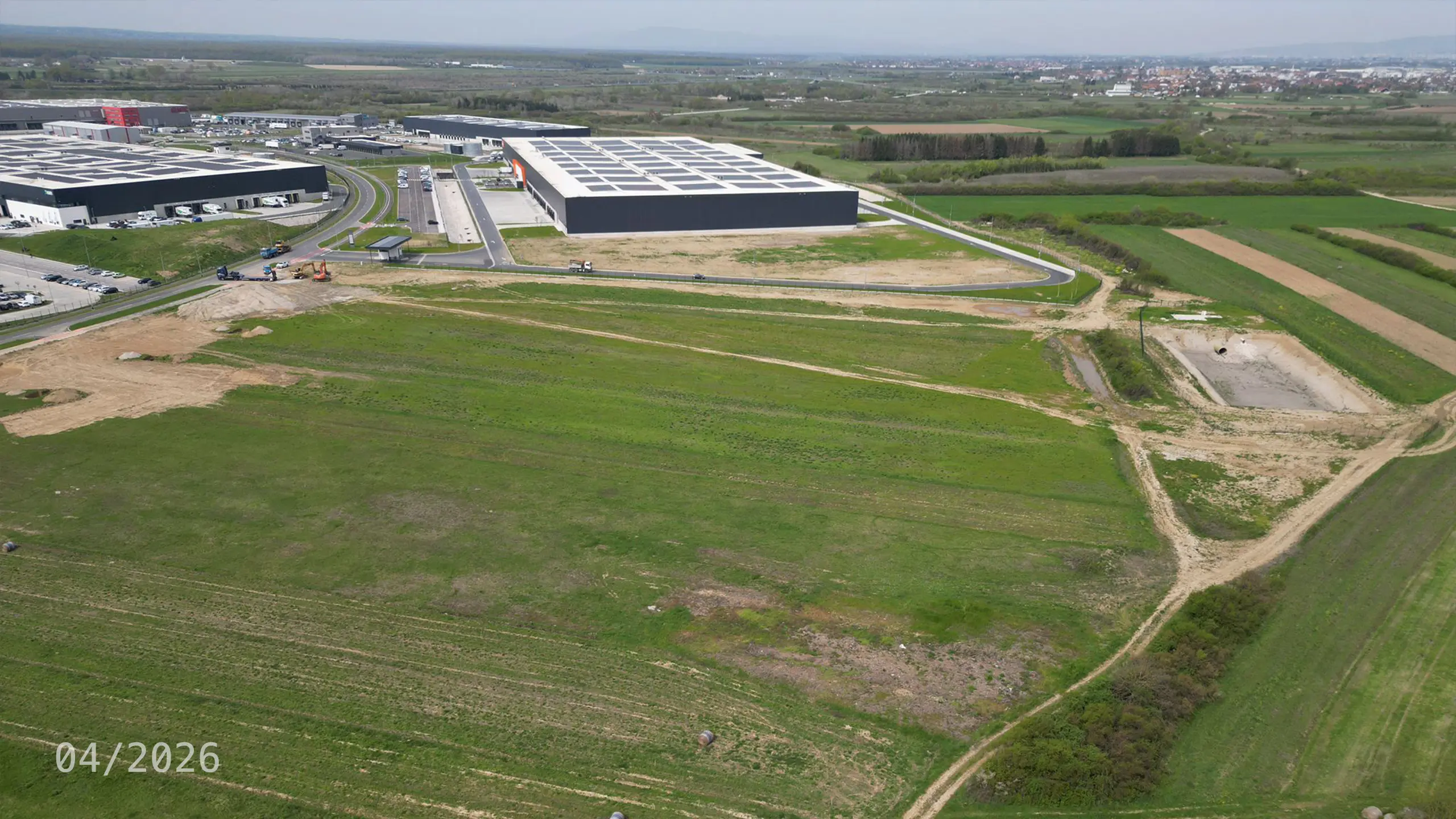 Industrial Project Zagreb 4 – aerial view of site preparation works for the fourth expansion phase of the Zagreb logistics park. The photograph shows land designated for new logistics facilities, construction equipment and connections to the existing industrial park infrastructure. Zagreb 4 builds on the previous development phases and will expand the supply of modern high-standard warehouse space with a focus on energy efficiency, photovoltaic systems and BREEAM certification. - obrázok 8